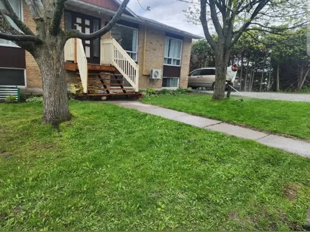 Terrain résidentiel entretenu devant un duplex de Sherbrooke, un employé de BW travaille près de l'entrée