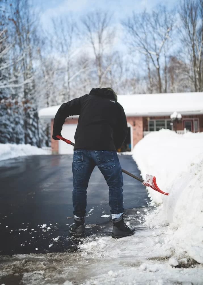 Déneigement manuel à la pelle d'une entrée résidentielle enneigée